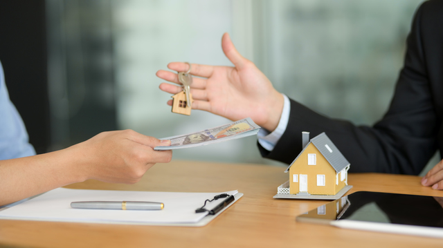 Close up view of real estate agent giving house key to customer